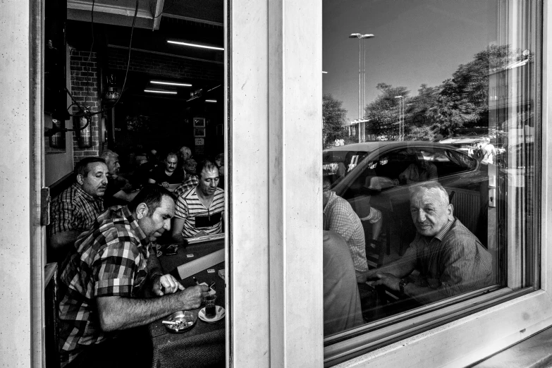 a man stands outside of a diner looking through the window