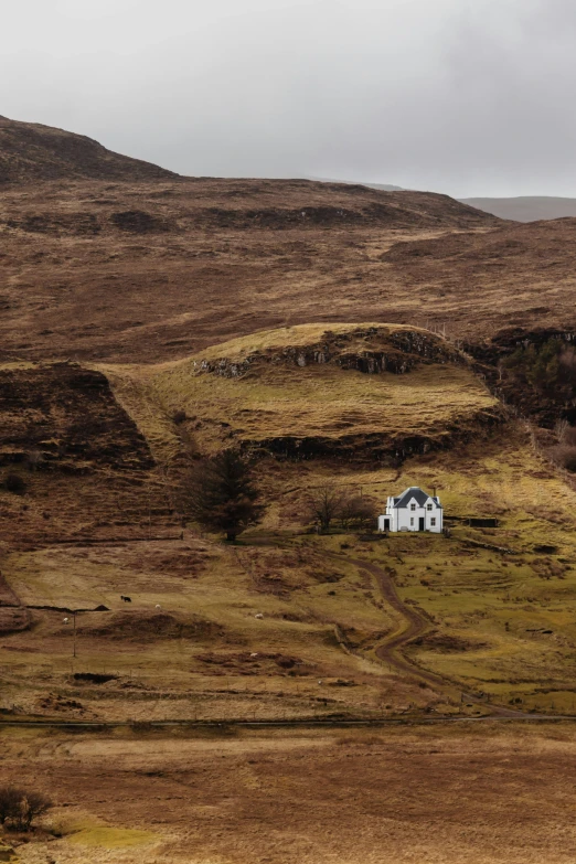 a single house in the field with brown grass