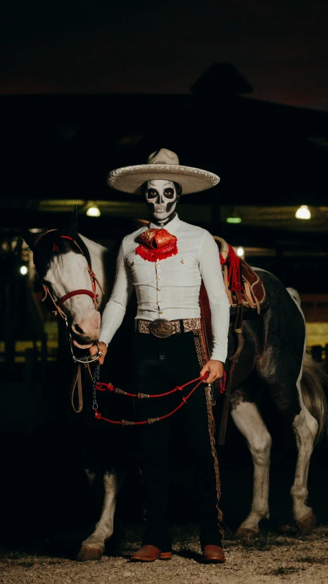 a mexican man dressed up as a skeleton standing beside a horse