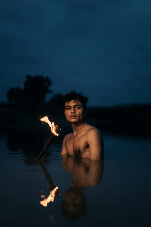 a man is posing in water with an illuminated stick