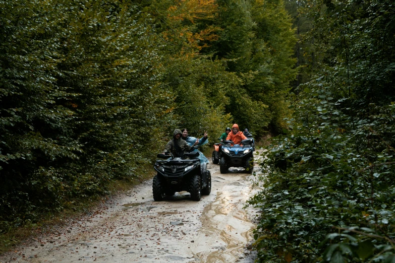 three atv riders on an overgrown dirt path