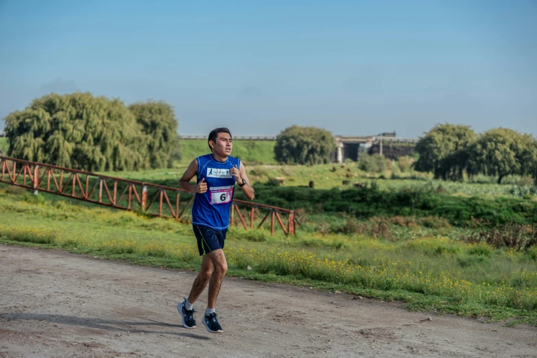 man running down dirt road with grass and trees