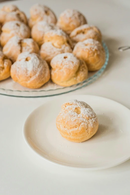 the white powdered doughnuts on the table are beside each other