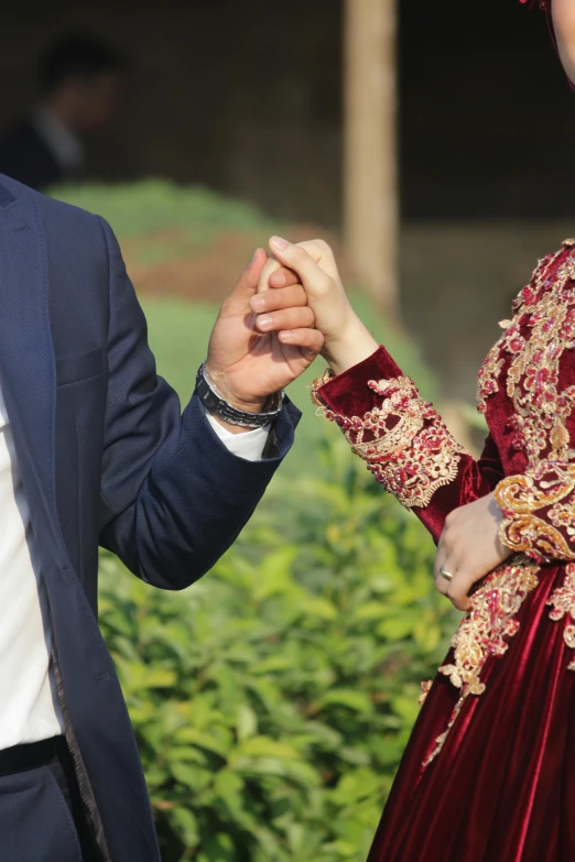 two people dressed in elaborately attire holding hands