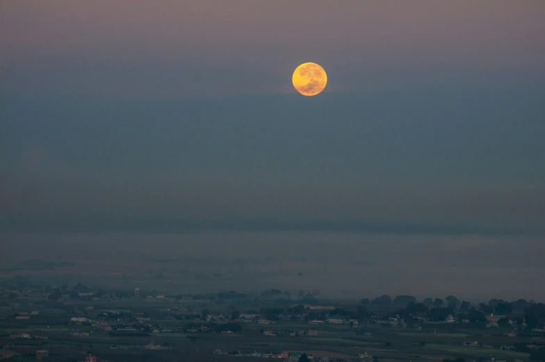 an airplane flying through the sky with a yellow moon behind it