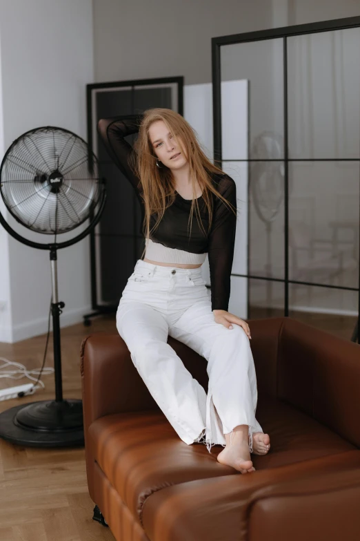 a woman sitting on a brown leather couch with her feet up