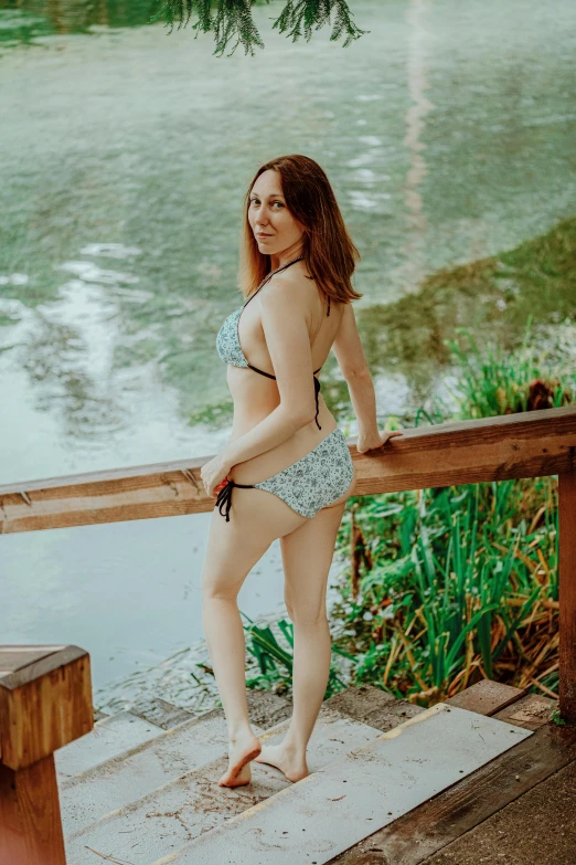 a woman in blue swimsuit standing by a railing