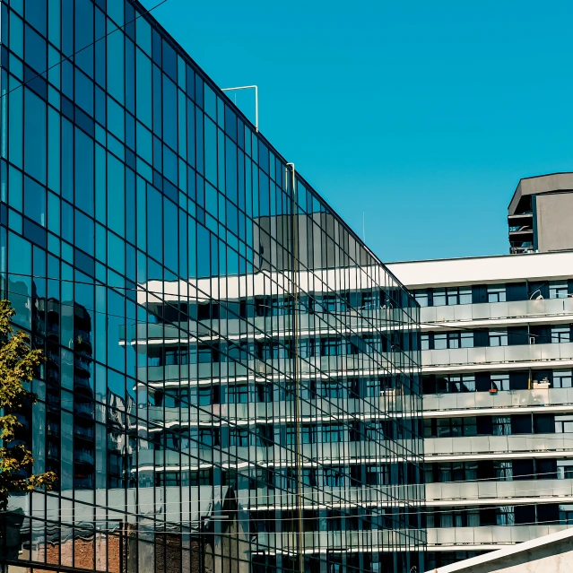 a modern glass building in a city with a tall clock tower