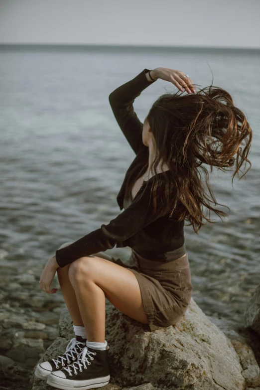 a young woman on the rocks near the water is posing