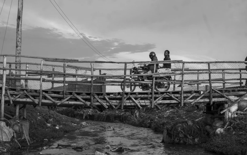 two people on a small bridge next to a stream