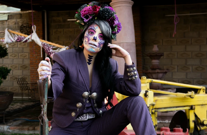 a woman wearing a mask and long black hair sitting on the ground