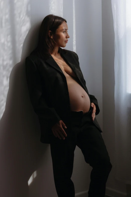 a woman in a suit poses in front of a white wall