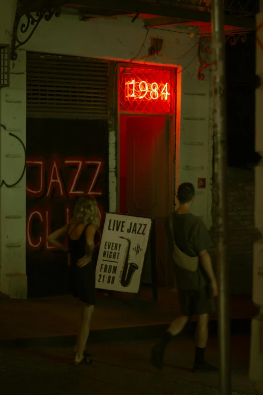 two people standing near a street with a sign for a jazz club