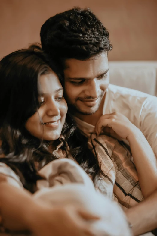 a woman hugging her man while he is on a white couch