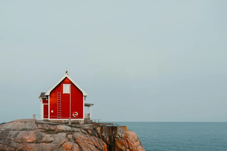 a small house is perched on top of the rock at the ocean