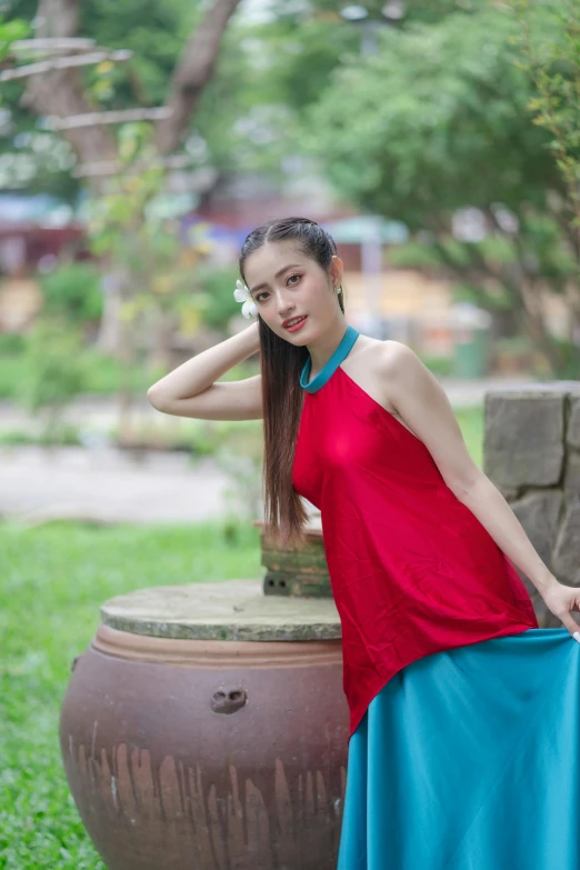 a beautiful woman standing next to a brown vase