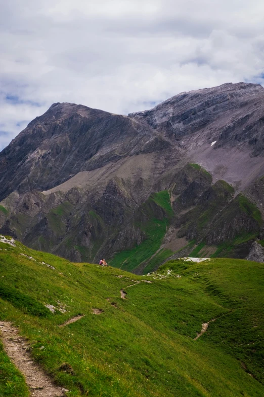 two people are walking up a trail in a mountain range