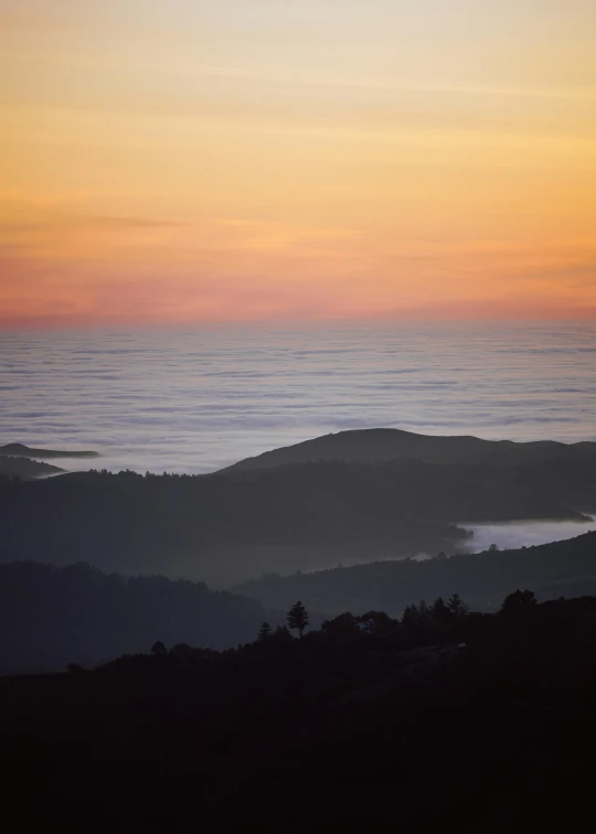 a mountain with trees at sunset overlooking the sky