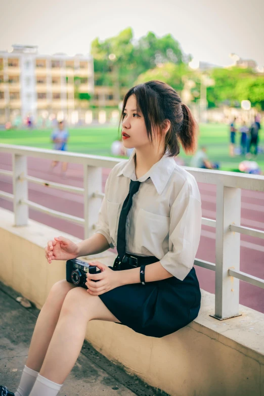 a woman in a dress sitting on top of a bench holding a camera