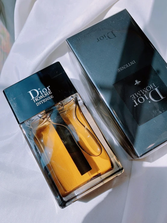 a bottle of perfume with its box opened on top of it