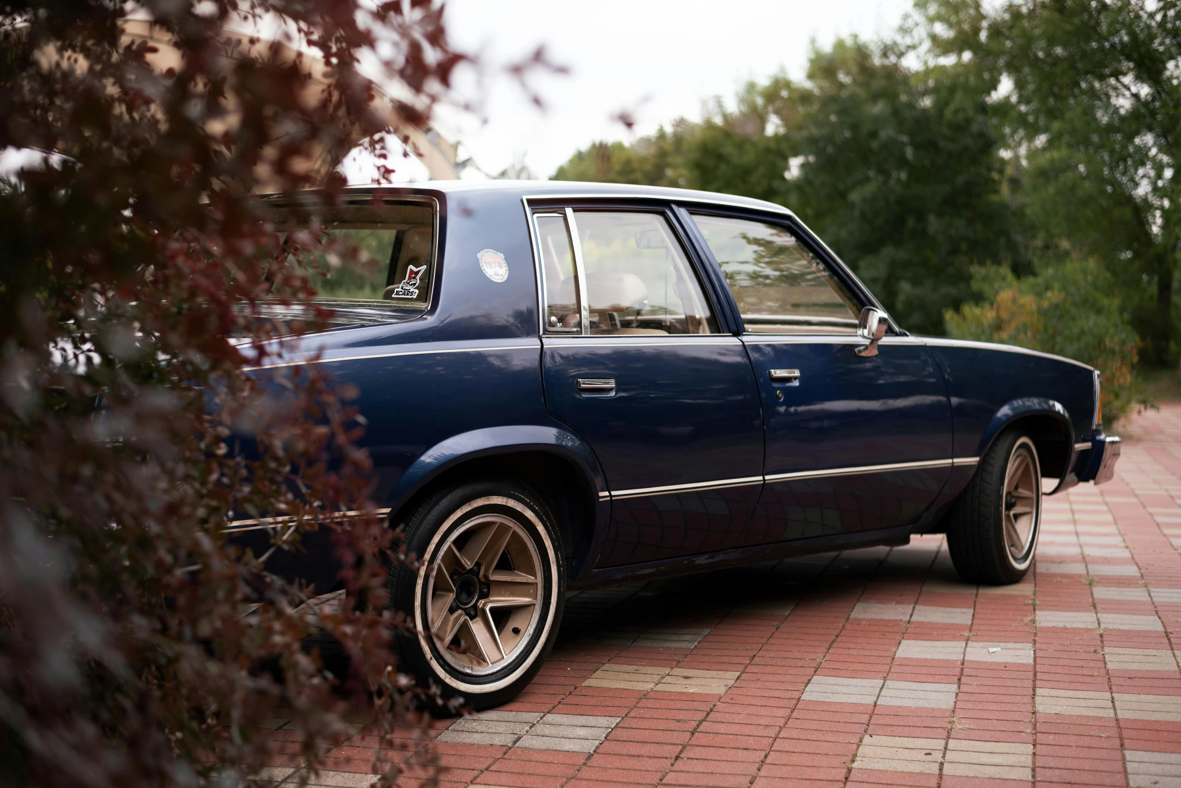 a blue station wagon is parked on a brick road