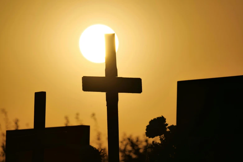 cross and sunset behind two residential buildings