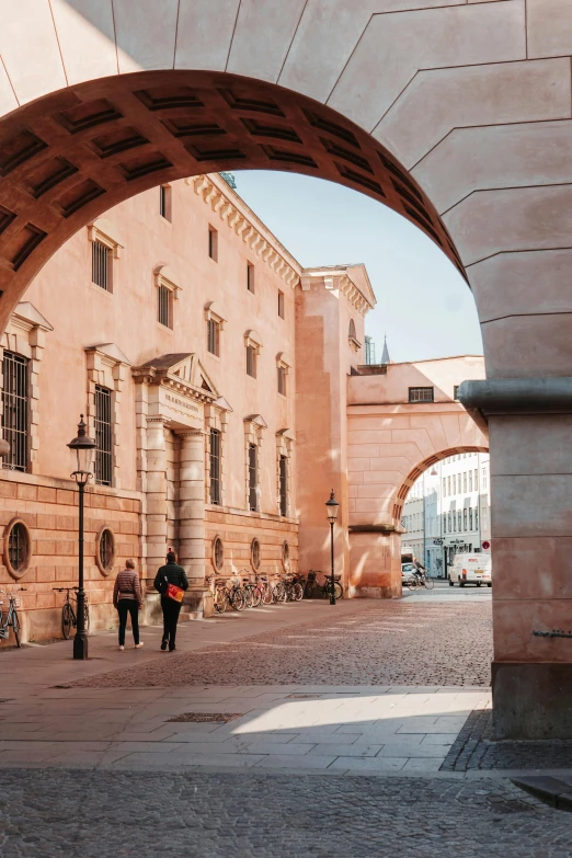 two people standing on a street under an arch