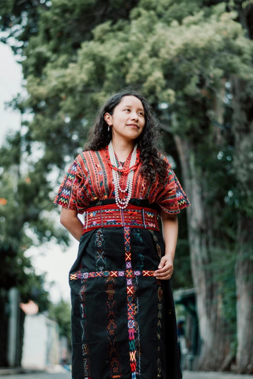 a woman with a tie standing by some trees