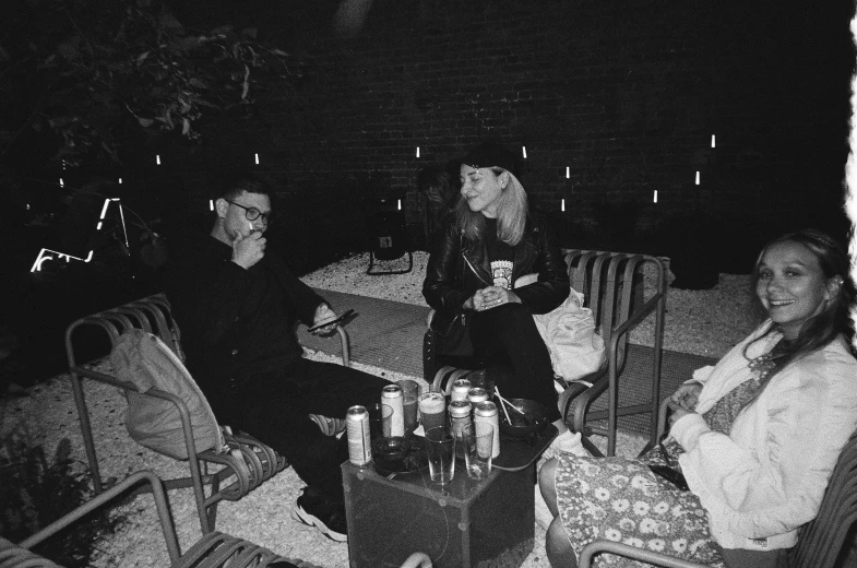 three people sitting at a table outside at night