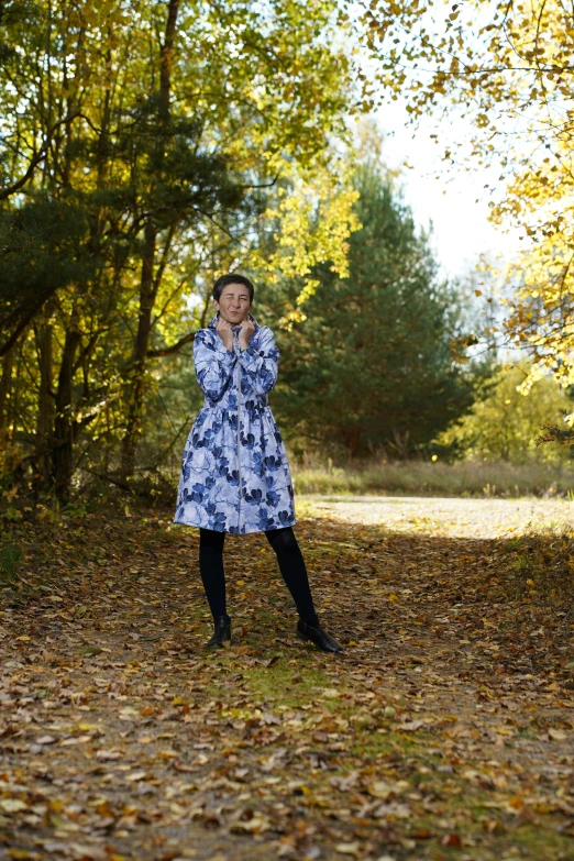 woman standing in autumn leaves with arms outstretched