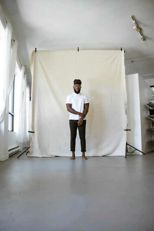 a black man wearing a white shirt standing in front of a light