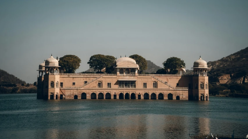 an ancient house sitting on a lake in the middle of a forest