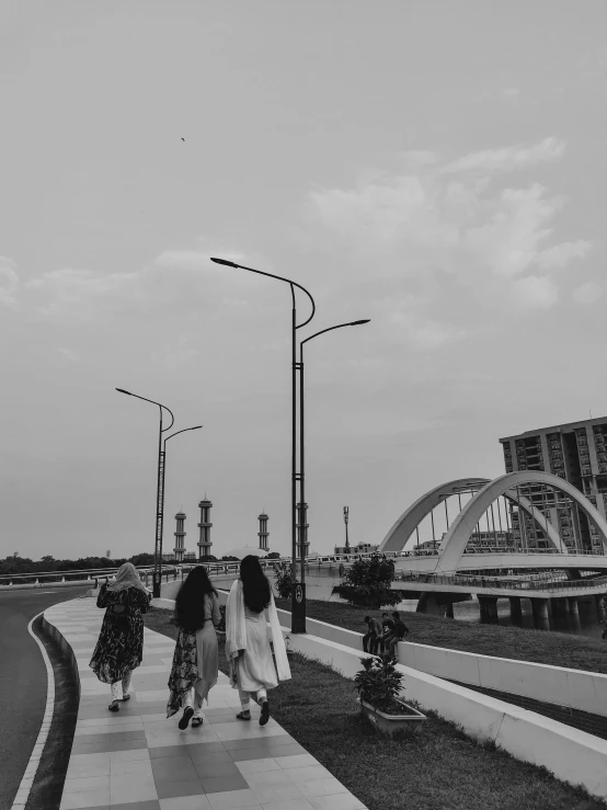 three women walk along a walkway towards a bridge