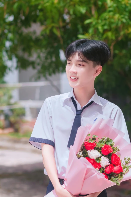 a man holding flowers next to green trees