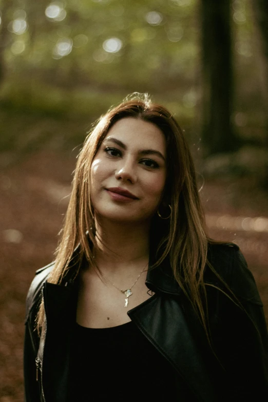 a woman with brown hair standing in the forest