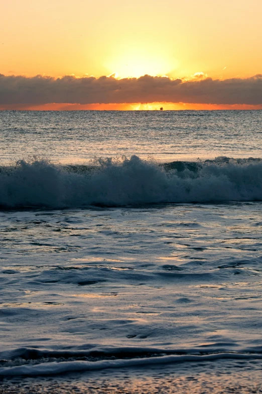 a surfer and their surfboard standing in the water at sunset