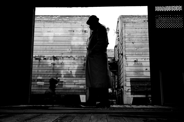 black and white pograph of man standing next to a wall