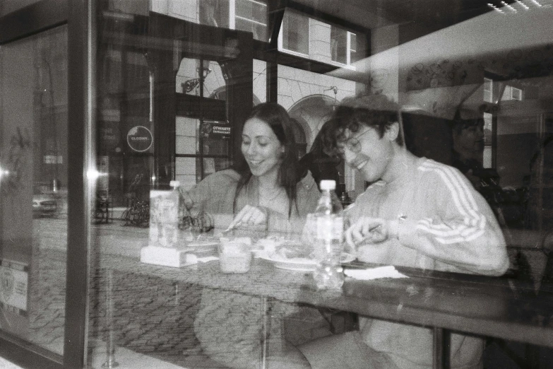 three people sitting at a table with a drink in front of them