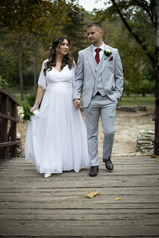 the bride and groom are holding hands walking down a bridge