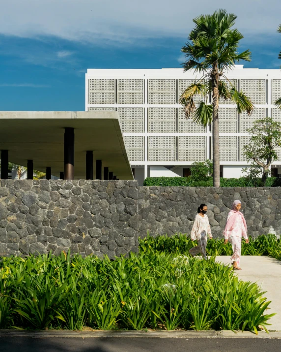 two women walking down a sidewalk between trees