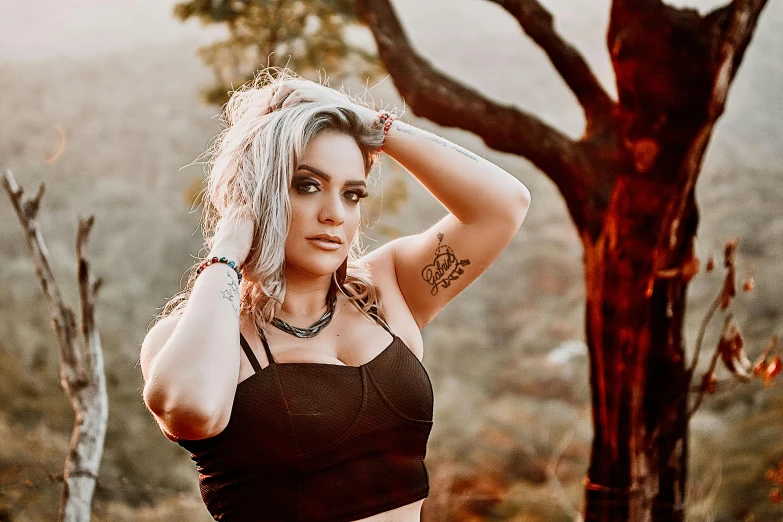 a woman with tattoos wearing a tank top in the woods