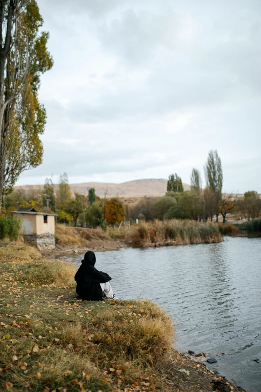 the person in black is fishing in the pond