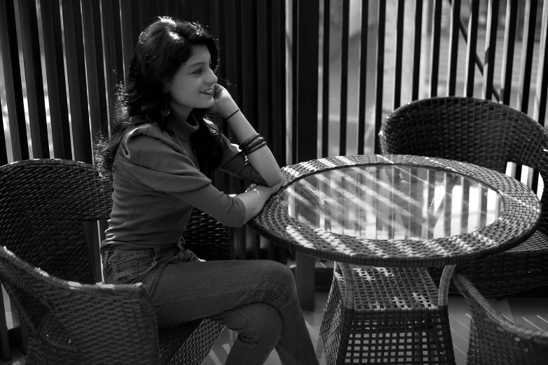 a woman sits at an outdoor table near her phone