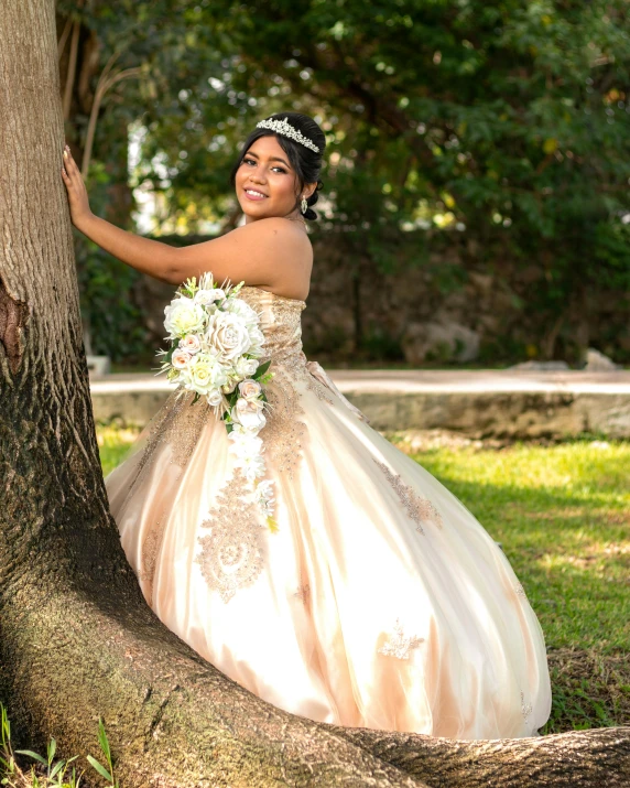 a smiling bride leaning on a tree