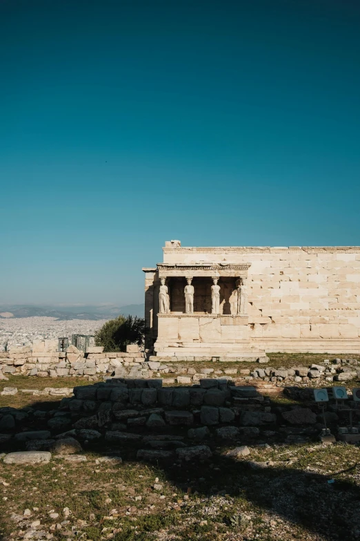 an ancient building with three pillars and grass