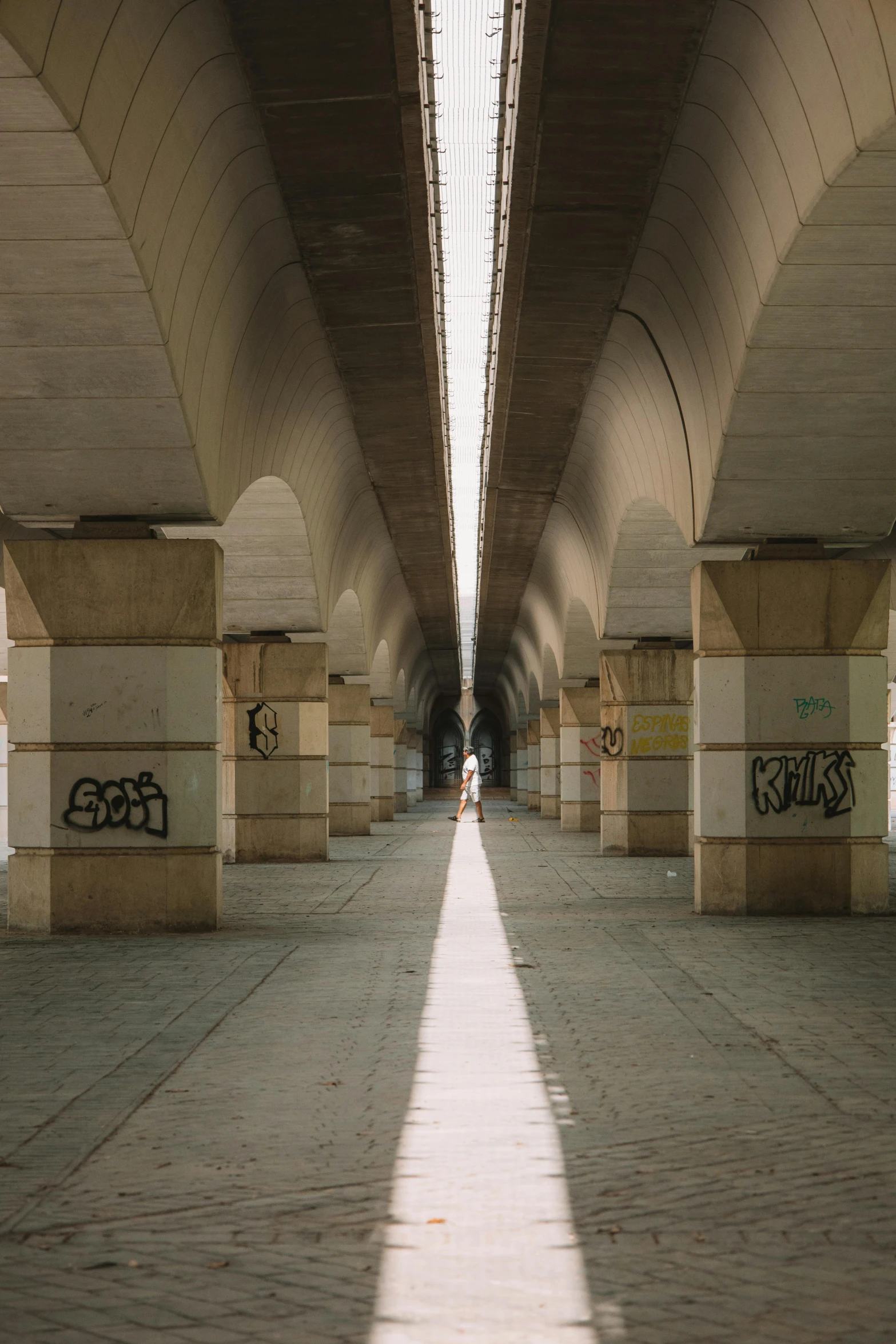 two people standing on the side walk under an overpass