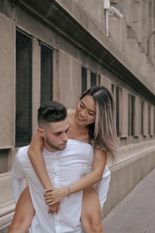 a beautiful young couple hugs while holding each other outside