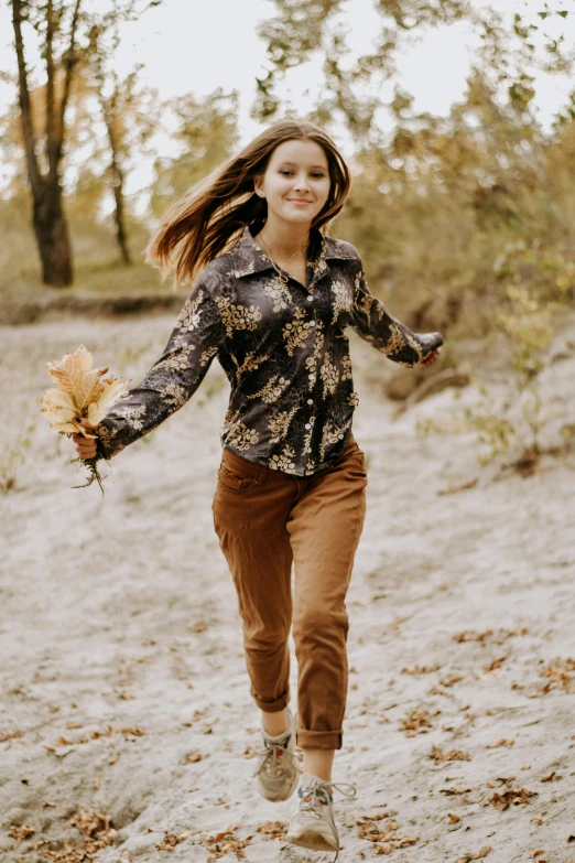 woman with brown pants, a black shirt and a bunch of flowers in her hands