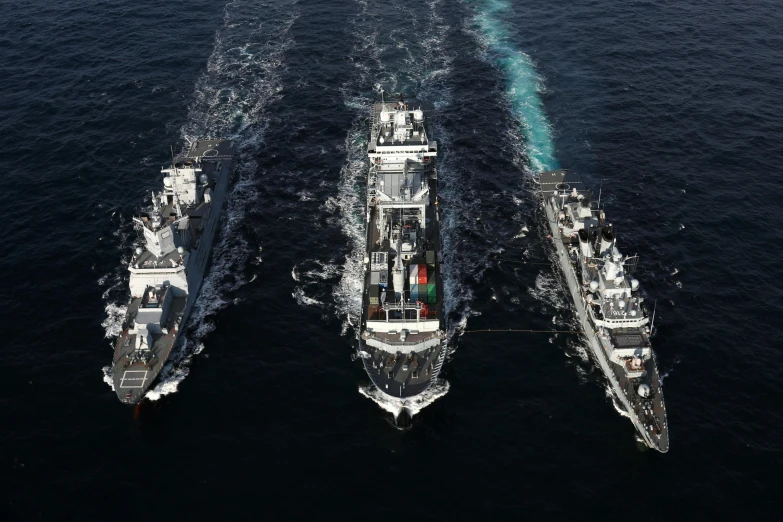 three large boats are in the water near one another