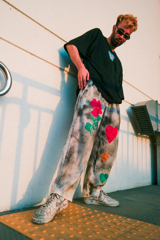 a man wearing sweatpants leaning against a wall